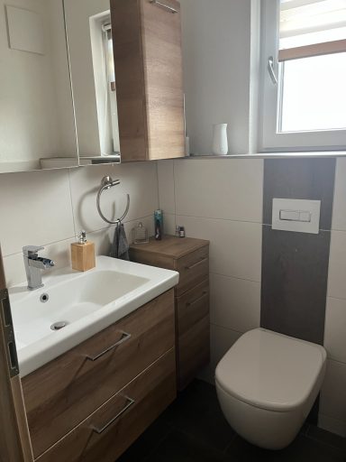 Modernes Badezimmer mit Waschbecken, Holzschränken und WC.