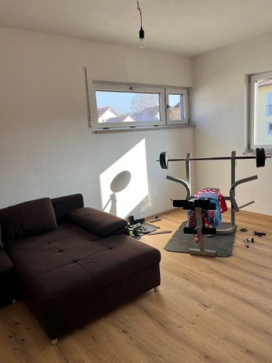 Ein helles Zimmer mit einer Couch und einer Fitnessstation.