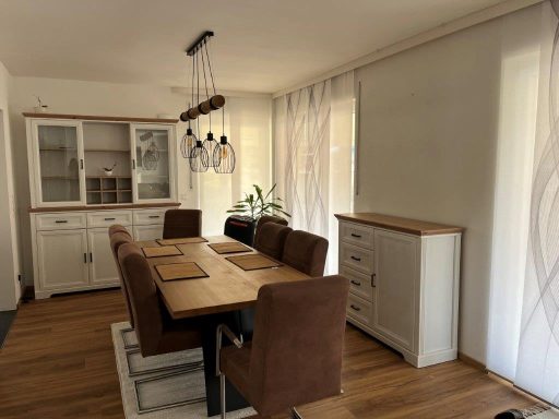 Moderne Esszimmer mit einem langen Tisch, braunen Stühlen und hellem Holzschrank.