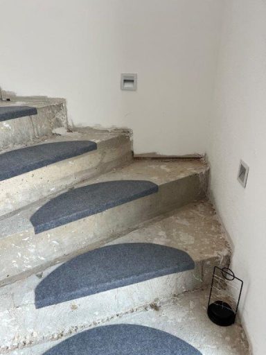 Graue Treppenstufen mit rutschfesten Streifen, in einem unvollendeten Raum.