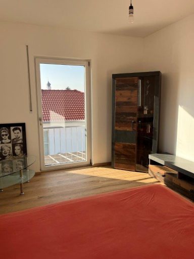 Heller Raum mit Holzfußboden, rotem Teppich und Balkonzugang.