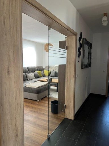 Blick auf einen hellen Flur mit Glastür zu einem Wohnzimmer und eleganter Einrichtung.